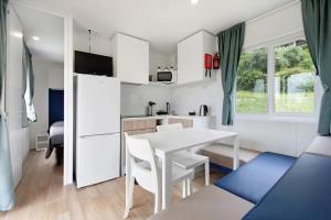 普雷多雷Camping Eurovil的厨房以及带白色桌椅的用餐室。