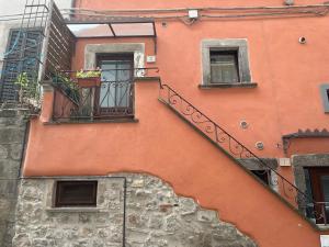 维泰博DOMUS TUSCIA APARTMENTS San Faustino guesthouse的一座橙色的建筑,设有楼梯和阳台