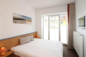 奥斯赛拜-屈隆斯博恩Strandschloesschen-Haus-I-WE-7-9866的卧室配有白色的床和窗户。