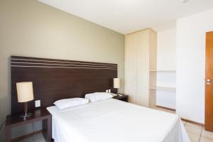 累西腓Flat Metropoles Ilha do Leite by Easy Home的卧室配有白色的床和木制床头板