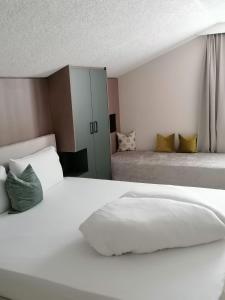 布兰德坦勒格加尼住宿加早餐酒店 的一间白色卧室,配有两张床和橱柜