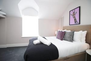 卡迪夫Stay with Free Parking at Archer Road Penarth的卧室配有一张带白色和紫色枕头的大床