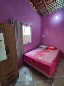 图托亚Recanto dunas的紫色卧室设有一张床和一个窗户