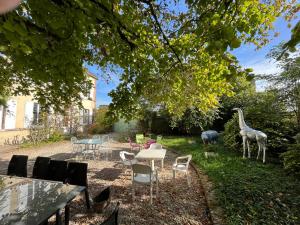 SormeryLa Demeure d'Othe的花园设有桌椅和长颈鹿雕像