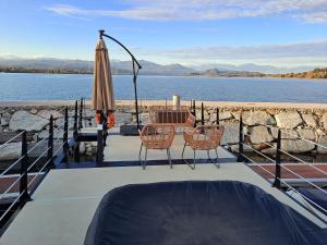 多尔梅莱托Floating Experience Black Pearl, Lago Maggiore的庭院配有桌椅和遮阳伞。