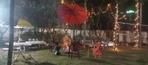 勒克瑙The Beatrix Resort & Wellness的庭院配有桌子和红色的雨伞及灯。