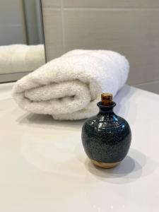 比埃什河畔阿斯普尔Villa Caprice à l'orée des bois的浴室内的一个柜台上的毛巾和花瓶