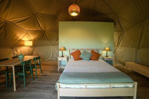 卡纳斯·德·塞尤里Manteiros Glamping的帐篷内的卧室,配有一张床和一张桌子
