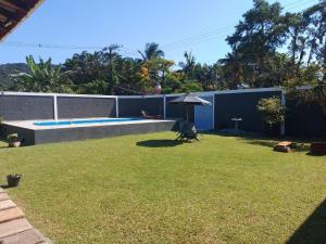 圣塞巴斯蒂安Hospedaria Morada das Orquídeas的后院设有游泳池和遮阳伞