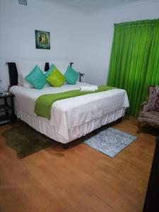 威廉王城Ezamampondo Guest House的一间卧室配有一张带绿色窗帘的大床