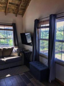 恩塞纳达港Casa de campo en la montaña (incluye 2 cabañas)的带沙发和2扇窗户的客厅