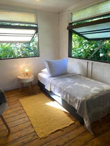 TemaeGreat House BY Manaeva Lodge的一间卧室设有床、两个窗户和地毯。