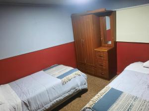 纳塔列斯港Hostal Nuria (Puerto Natales,Chile)的一间卧室设有两张床和木制橱柜