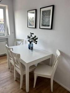 奥伯豪森Wohnung am CentrO!的白色的餐桌、椅子和花瓶