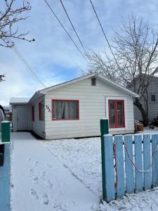 怀特霍斯Entire House and Home in Whitehorse Downtown的雪上设有红色窗户的白色房子