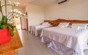 奥兰布拉Rancho da Cachaça Pousada的一间带两张床的卧室和鲜花花瓶