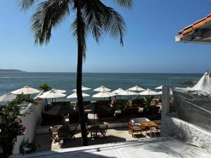 卡塔赫纳Wala beach club的海滩上设有桌子和遮阳伞,还有大海