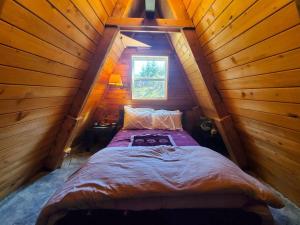 朱诺Douglas Island A-frame Cabin in the Woods的木制客房的一张床位,设有窗户