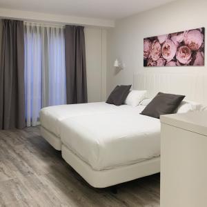 卡里翁德洛斯孔德斯Hostal Comfort Suites的卧室配有一张白色大床和一幅画