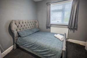 Great BursteadAlaya’s home的小卧室配有一张带蓝色棉被的床和窗户