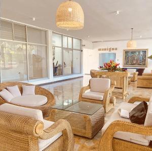比亚维森西奥拉诺酒店的一间客厅,客厅内配有藤椅和桌子,位于商店