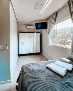 弗洛里亚诺波利斯Morada da Lagoinha的一间卧室设有一张床、一台电视和一个窗口。