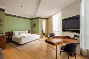 上海上海素凯泰酒店的一间卧室配有一张床、一张书桌和一台电视。