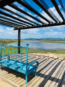 尚格里拉Espaço encantador na Lagoa- Morada colorida: lugar de gente feliz!的蓝色长椅,坐在水边的甲板上