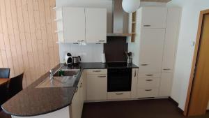 因内特基尔兴Wohnung mit 3 Schlafzimmern Wylerdümen的厨房配有白色橱柜和黑色台面