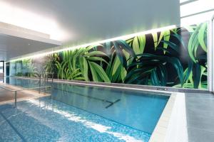 奥克兰The Grand by SkyCity的墙上挂有植物壁画的游泳池