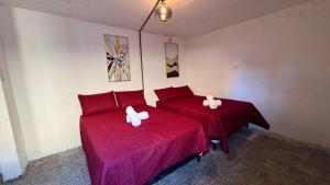 危地马拉CASA MAGNOLIA的宿舍间的两张床,配有红色的床单和毛巾