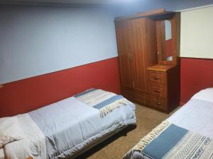 纳塔列斯港Hostal Nuria (Puerto Natales,Chile)的一间卧室设有两张床和木制橱柜