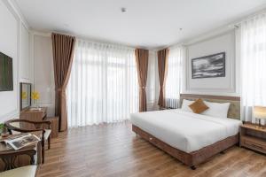 大叻PINE VIEW Hotel Dalat的卧室配有一张白色大床和一张书桌
