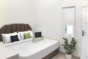 PaalmerahUrbanview Hotel Syariah near Polda Jambi的白色卧室,配有一张带笔记本电脑的床