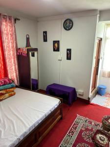 GhumKunsang Homestay的卧室配有一张床,墙上挂着一个钟