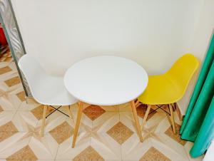 蒙巴萨Seaside Heights 2BR 43' Smart TV的一张白色的桌子和两张黄色的椅子