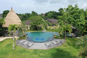 坎古Lalasa Villas Canggu的享有带椅子和茅草屋顶的游泳池的顶部景致