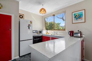 皮克顿Coastal Charm - Picton Holiday Home的厨房配有白色冰箱和红色橱柜