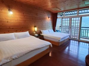 鹿谷乡金台湾山庄的配有木墙和窗户的客房内的两张床