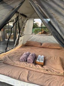 拜县Pai Chao Kha的帐篷内的一张床位,配有毛巾和拖鞋