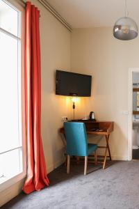巴黎巴蒂诺勒酒店的客房设有一张带蓝椅的书桌和一台电视。