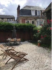 鲁昂Maison individuelle dans ancienne ecurie的一个带遮阳伞和桌椅的房子