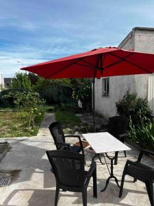 布尔日studio avec jardin et stationnements的一个带桌子和红色遮阳伞的庭院