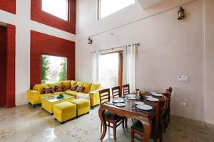 GuntaAlaya Stays 3 BHK Farmhouse wit Pvt Pool & Garden - Anantara的一间带桌子和黄色椅子的用餐室