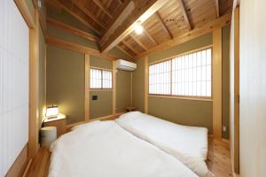 镰仓市一棟貸しの宿 寂香庵的卧室设有一张白色大床和两个窗户。