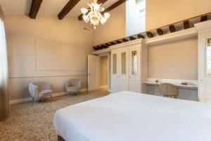 威尼斯San Vio Palace Luxury Apartments的卧室配有一张白色大床和椅子