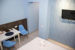 阿拉木图AG Hotel的客房设有一张桌子、蓝色的椅子和一台电视机。