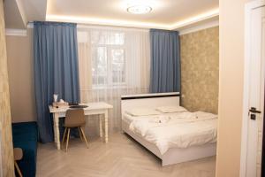 阿拉木图AG Hotel的一间卧室配有一张床、一张书桌和一个窗户。