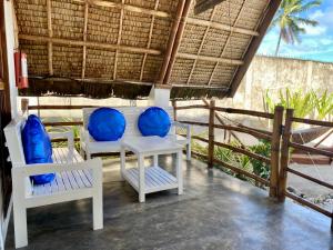 AborlanSurya Beach Resort Palawan的门廊配有白色椅子和蓝色靠垫