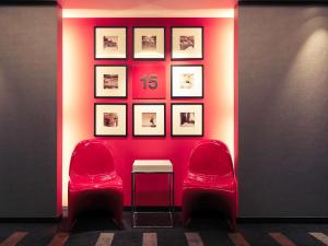 札幌札幌美居酒店的一间设有两把椅子和一张桌子的房间,以及一张带照片的墙壁